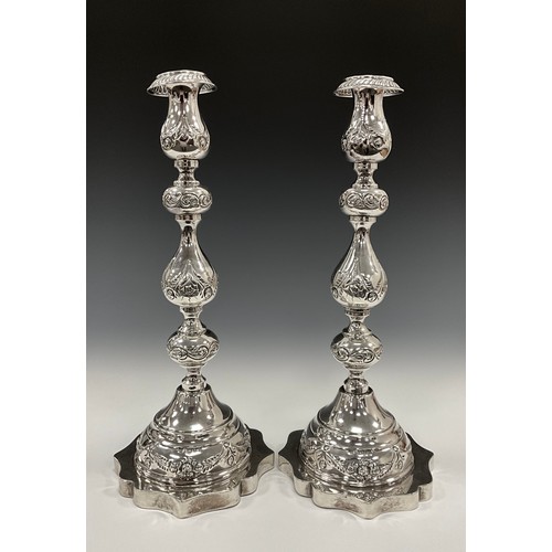 186 - Judaica - a pair of large George V Jewish Sabbath candlesticks, embossed with floral swags and scrol... 