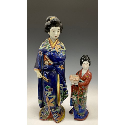 1206 - A Japanese Export ware porcelain figure, of a Geisha holding a fan, painted in polychrome and picked... 