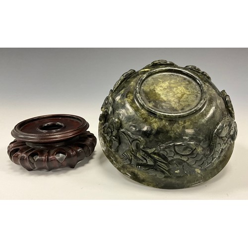 1423 - A Qing period Chinese spinach jade bowl on stand, flared rim, the sides carved with dragons, hardwoo... 