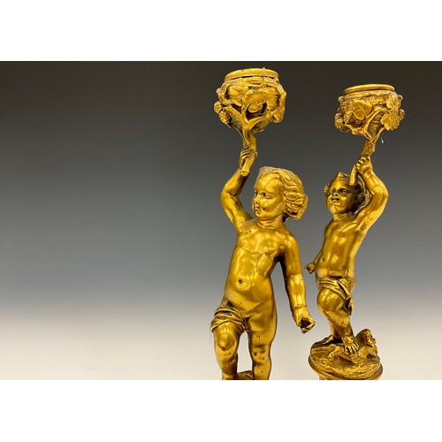 1846 - A pair of 19th century gilt metal figural candlesticks, each cast as a scantily clad putto, 26cm hig... 