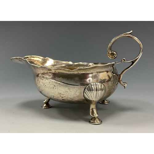 267 - A George II silver sauce boat, shaped rim, scrolled handle, shell and pad feet, London 1749, indisti... 