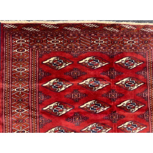 2073 - A Turkman rug, typical repeating Göl pattern, in rich tones of red, with white and black accents, 17... 