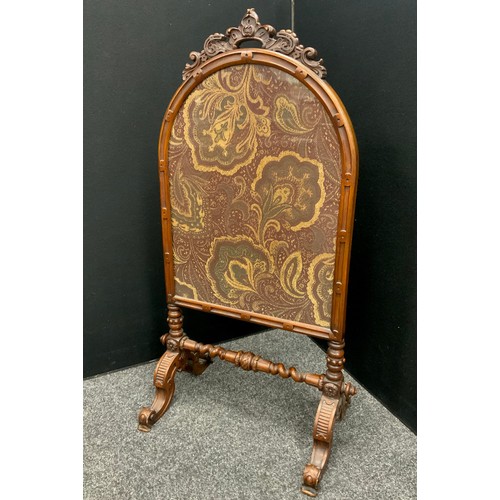 1565 - A Victorian walnut carved firescreen, arched floral crest, inset with floral needlework panel in ton... 