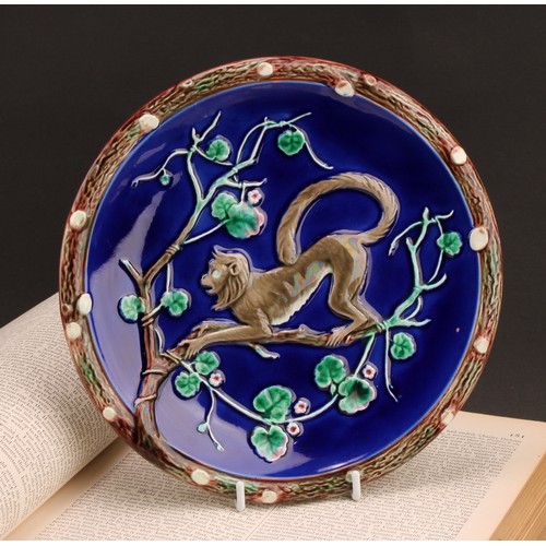 1344 - A Wedgwood Majolica small plate, moulded with a monkey clambering among flowering branches, on a blu... 