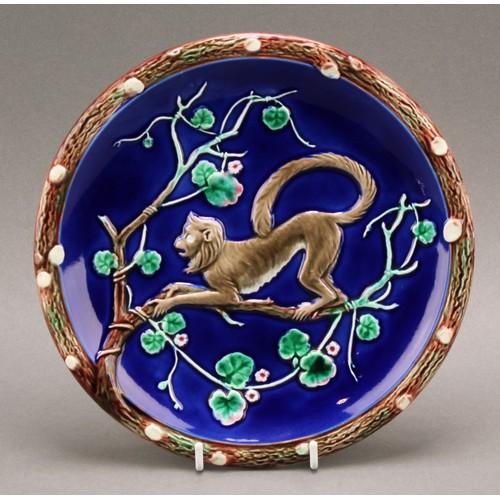 1344 - A Wedgwood Majolica small plate, moulded with a monkey clambering among flowering branches, on a blu... 