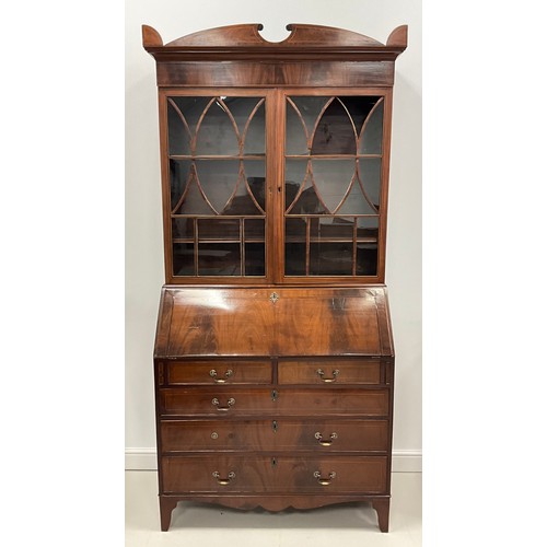 1911 - A Sheraton Revival mahogany bureau bookcase, shaped pediment above a pair of astral glazed doors enc... 