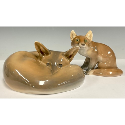 12 - A Royal Copenhagen porcelain model, of a curled up fox, shape no. 438, 17cm wide; a Bing & Grondahl ... 