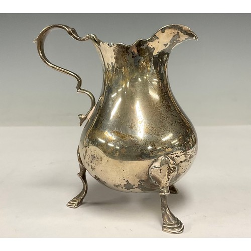 42 - An Edwardian silver baluster cream jug, shaped rim, three pad feet, 10cm high, London 1902. 156g