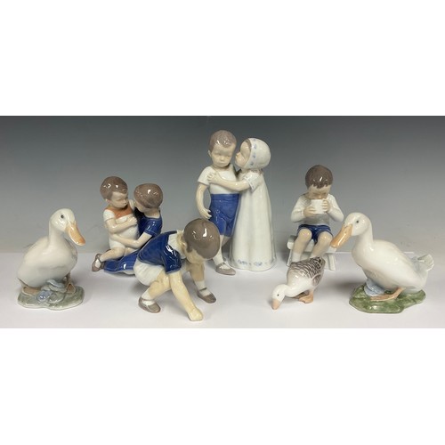 75 - A Bing & Grondahl porcelain figure group, Girl Kisses Boy, shape no. 1614, 17cm high; others, Boy on... 