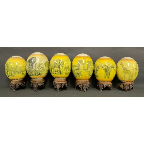 77 - A set of six Ostrich eggs, each decorated with an African animal, including Rhinoceros, Elephants, G... 