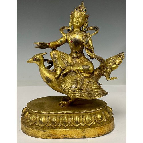 514 - A gilt bronze jewelled figure, as a seated Buddha riding on a peacock, oval lotus base, 17cm wide, 2... 