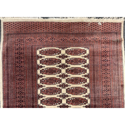 192 - A Turkmen type rug, hand-knotted in tones of red, black, and taupe, 127cm x 184cm.