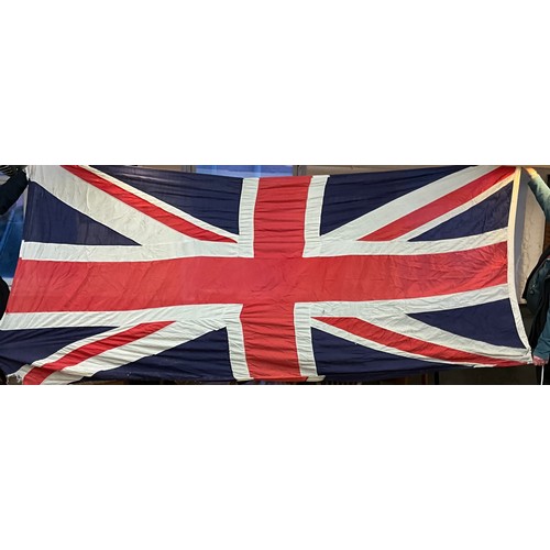 53 - A Union Jack flag, 155cm x 340cm;  and a framed display of a lady wearing samples of fabric produced... 