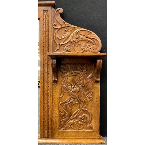 449 - An early 20th century carved oak over-mantle mirror, the side panels and cresting carved in relief w... 