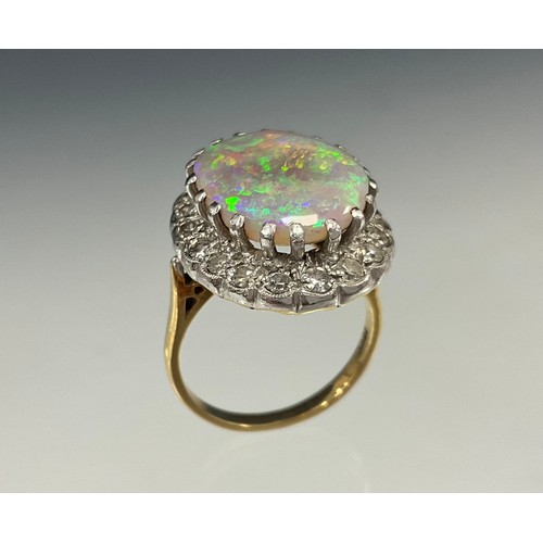 909 - An impressive opal and diamond cluster ring, large oval opal cabochon approx 17mm x 13mm flashing vi... 