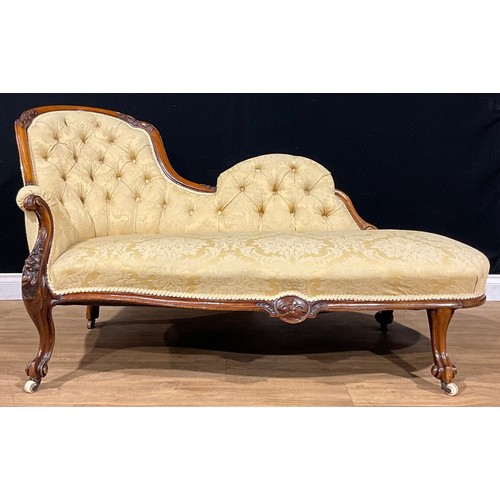 2464 - A Victorian walnut chaise longue, stuffed-over upholstery, the frame carved with bell husks and flow... 