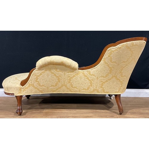 2464 - A Victorian walnut chaise longue, stuffed-over upholstery, the frame carved with bell husks and flow... 