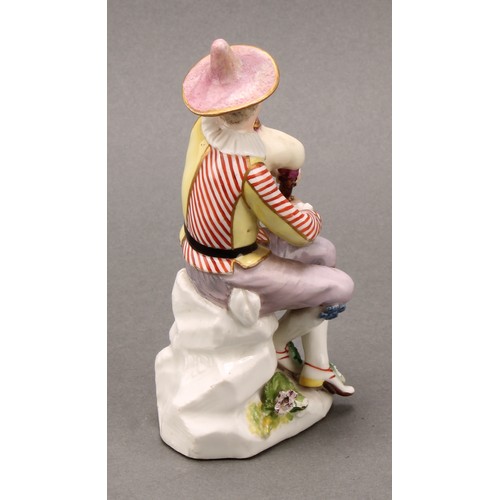 280 - An 18th century porcelain figure, Harlequin, he sits with bagpipes, blue crossed sword mark, 13.5cm ... 