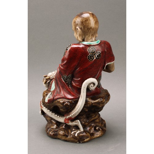 1298 - A Japanese porcelain figure, of a sage holding the pearl of wisdom, a dragon at his side, decorated ... 