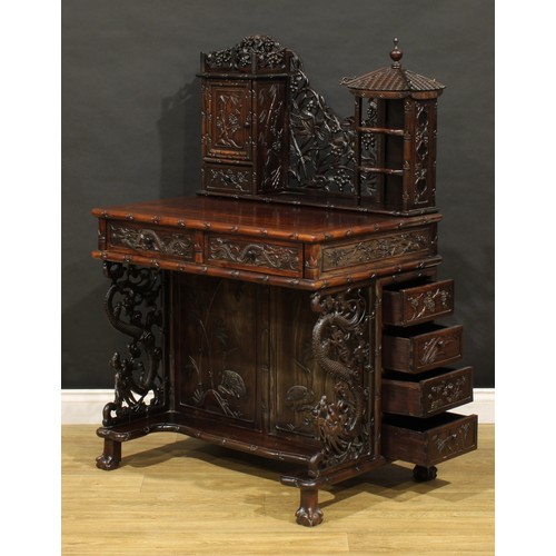 1891 - A Chinese export hardwood desk, shaped superstructure with panel door, small drawer and open shelves... 