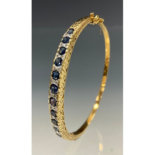 1201 - A diamond and sapphire hinge bangle, alternate set with graduated blue sapphires and pairs of round ... 