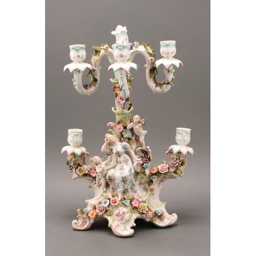 223 - A Continental porcelain figural five-branch candelabra, as a maiden seated beside a tree, with two c... 