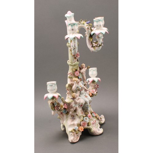 223 - A Continental porcelain figural five-branch candelabra, as a maiden seated beside a tree, with two c... 