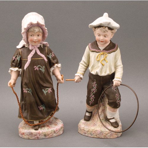 243 - A pair Gebrüder Heubach bisque figures, of a boy and girl at play, he with hoop and stick, she with ... 