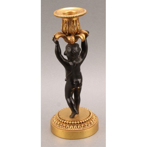 2083 - A pair of French Bronze and ormolu candlesticks, bronze cherub columns arms erect holding a gilt lea... 