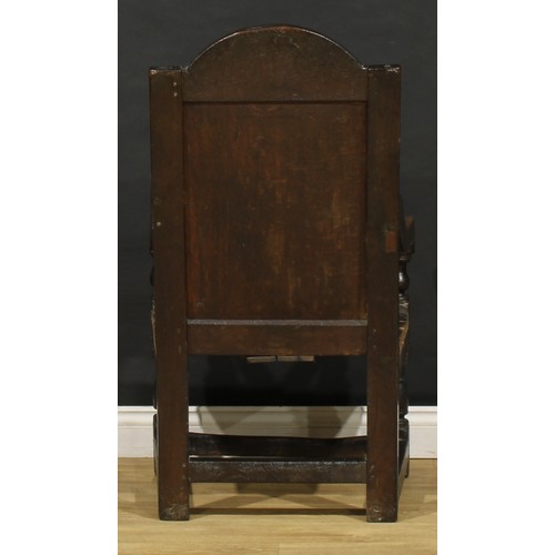 1880 - A 17th century oak wainscot armchair, carved panel back with arched cresting, downswept arms, turned... 