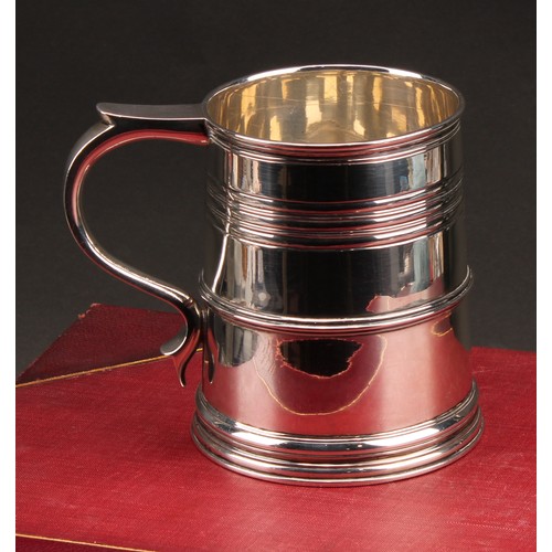 902 - A Queen Anne style silver slightly spreading cylindrical mug, moulded rim above reeded bands, skirte... 