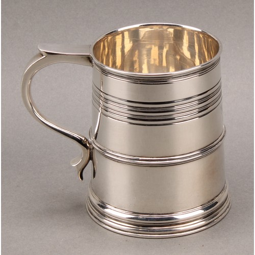 902 - A Queen Anne style silver slightly spreading cylindrical mug, moulded rim above reeded bands, skirte... 