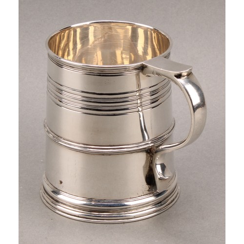 902 - A Queen Anne style silver slightly spreading cylindrical mug, moulded rim above reeded bands, skirte... 