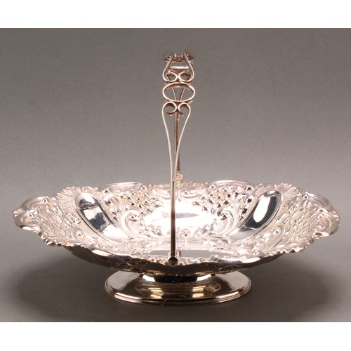 849 - A late Victorian silver swing-handled shaped oval pedestal basket, chased throughout with flowers an... 