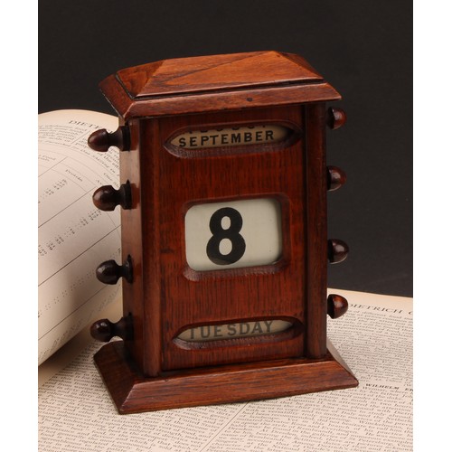 2345 - An early 20th century oak perpetual desk calendar, sarcophagus cresting above glazed apertures for d... 