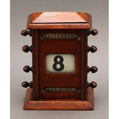 2345 - An early 20th century oak perpetual desk calendar, sarcophagus cresting above glazed apertures for d... 