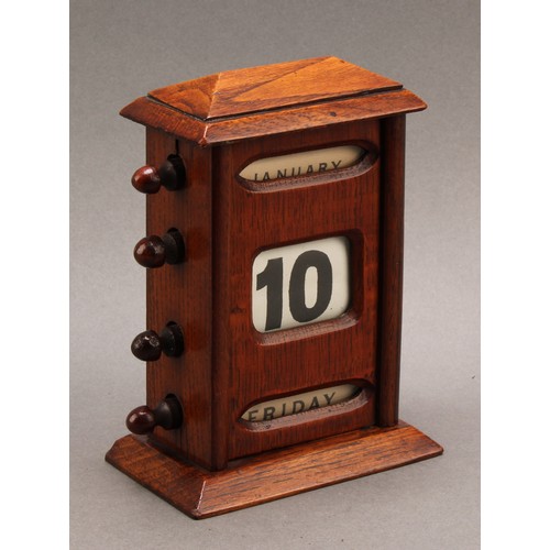 2345 - An early 20th century oak perpetual desk calendar, sarcophagus cresting above glazed apertures for d... 