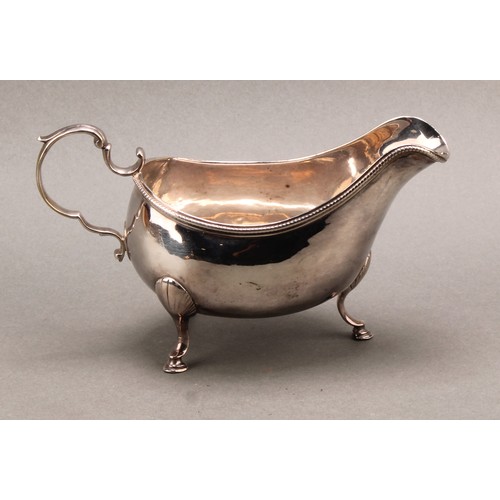 766 - A George III Irish silver sauceboat, acanthus-capped scroll handle, beaded rim, hoof feet with shell... 