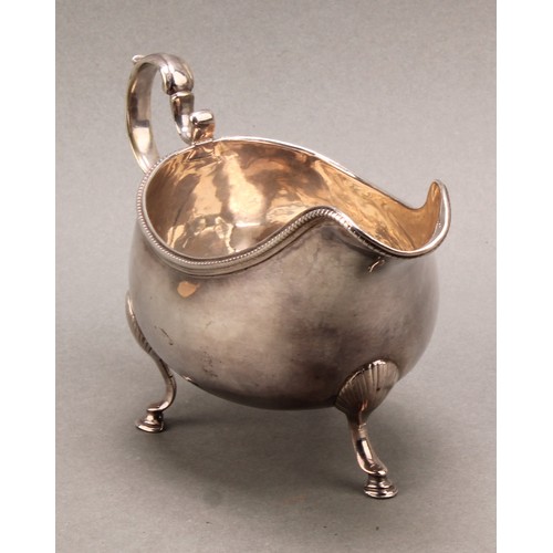 766 - A George III Irish silver sauceboat, acanthus-capped scroll handle, beaded rim, hoof feet with shell... 