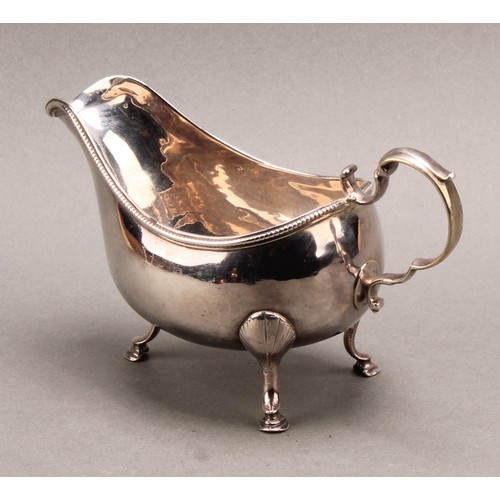 766 - A George III Irish silver sauceboat, acanthus-capped scroll handle, beaded rim, hoof feet with shell... 