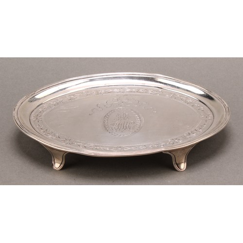 783 - A George III silver oval teapot stand, bright-cut engraved, reeded border, outswept feet, 16.5cm wid... 