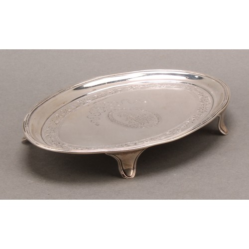 783 - A George III silver oval teapot stand, bright-cut engraved, reeded border, outswept feet, 16.5cm wid... 