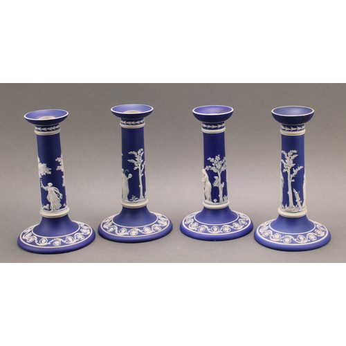 104 - A pair of Victorian Wedgwood Jasperware candlesticks, typically sprigged in white with classical sce... 