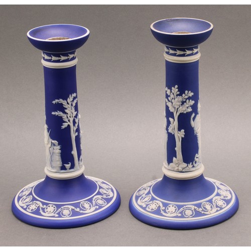 104 - A pair of Victorian Wedgwood Jasperware candlesticks, typically sprigged in white with classical sce... 