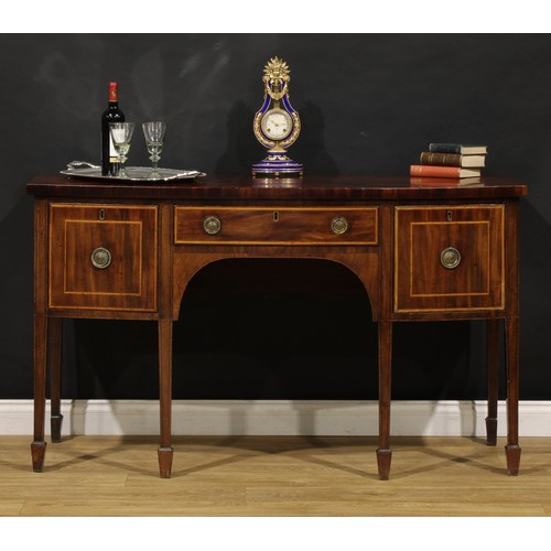 1504 - A George III mahogany bowfront sideboard or serving table, slightly oversailing top above three draw... 