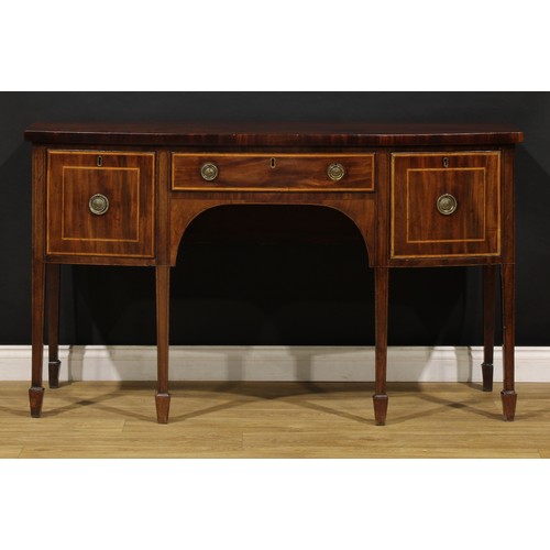 1504 - A George III mahogany bowfront sideboard or serving table, slightly oversailing top above three draw... 