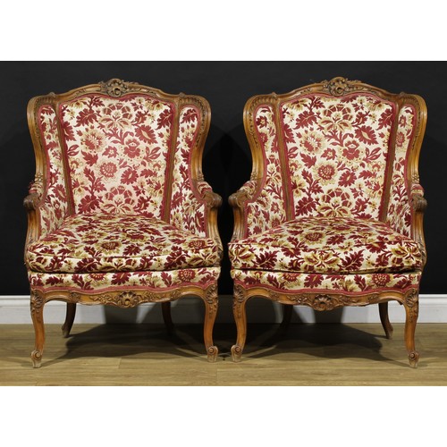 2411 - A pair of Louis XV Revival wing chairs, each with stuffed-over upholstery, squab cushion, cabriole l... 