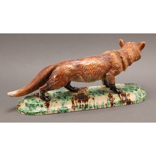 221 - A Continental model, of a fox, the base 'sponged' in mottled tones of green, yellow and brown, 36cm ... 