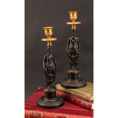 2436 - A pair of 19th century Grecian Revival parcel gilt and dark patinated bronze figural candlesticks, c... 