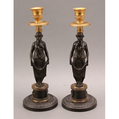 2436 - A pair of 19th century Grecian Revival parcel gilt and dark patinated bronze figural candlesticks, c... 